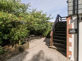 An outdoor area with stairs leading to a building and a small table with chairs under a tree at The Hayloft in Lostwithiel