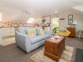A living room with a blue sofa and yellow chair next to a wooden chest and dresser at The Hayloft in Lostwithiel