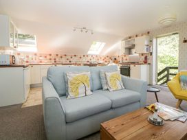 A living area with a light blue sofa and a wooden coffee table next to a kitchen with a tiled backsplash at The Hayloft in Lostwithiel