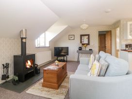 A living room with a wood-burning stove a television a wooden chest coffee table and a sofa at The Hayloft in Lostwithiel
