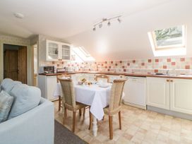 A kitchen with a dining table and chairs next to a sofa under skylights at The Hayloft in Lostwithiel