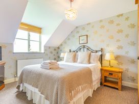 A bedroom with a bed bedside tables lamps and a window at The Hayloft in Lostwithiel