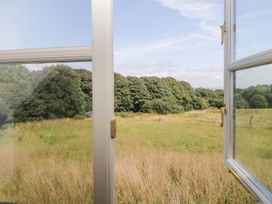 An open window overlooking a grassy field and trees at The Hayloft in Lostwithiel