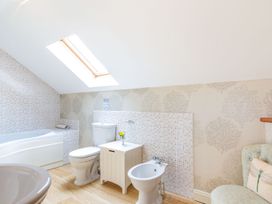 A bathroom with a bathtub toilet bidet sink and chair at The Hayloft in Lostwithiel
