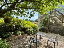 A garden with a table and chairs under a tree at The Hayloft in Lostwithiel