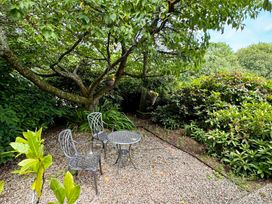 A garden area with table and chairs surrounded by greenery at The Hayloft in Lostwithiel