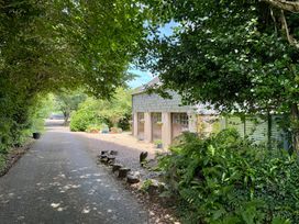 A driveway leading to a garage with trees and flowers at The Hayloft in Lostwithiel