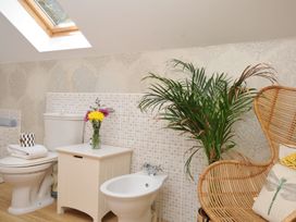 A bathroom with a toilet, bidet, sink, and chair at The Hayloft in Lostwithiel