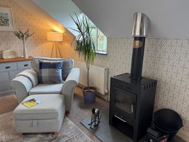 A snug with an armchair, ottoman, stove, and plant at The Hayloft in Lostwithiel