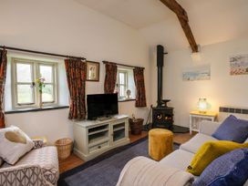 A living room with a wood burning stove a television and sofas at The Mill in Lostwithiel