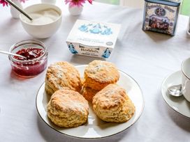 A plate of scones with clotted cream and jam on a table with a cup and sugar bowl at The Mill in Lostwithiel