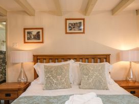 A bedroom with a wooden bed frame two patterned pillows bedside tables and lamps at The Mill in Lostwithiel