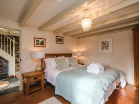 A bedroom with a wooden bed bedside tables lamps and a chandelier at The Mill in Lostwithiel