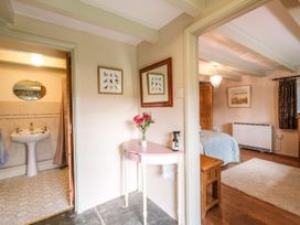 A hallway with a small table holding flowers and a spray bottle next to a bathroom and a bedroom at The Mill in Lostwithiel