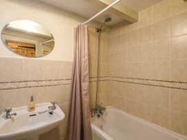 A bathroom with a bathtub shower combination and a sink with a round mirror above it at The Mill in Lostwithiel