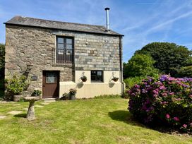 An outdoor view of a stone building with a slate roof and garden at The Mill in Lostwithiel