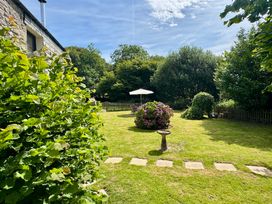 A garden with a flower bed and umbrella at The Mill in Lostwithiel