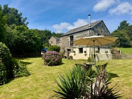 An outdoor area with a house, garden, table, and umbrella at The Mill in Lostwithiel