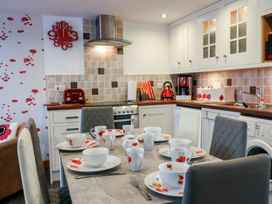 A kitchen with a dining table set with cups bowls and plates with poppy designs at Poppy Cottage in Aylesbeare