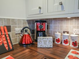 A kitchen countertop with a red kettle coffee maker knife set and labeled containers at Poppy Cottage in Aylesbeare