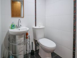 A bathroom with a sink, mirror, toilet, soap dispenser, and toilet paper at Poppy Cottage in Aylesbeare