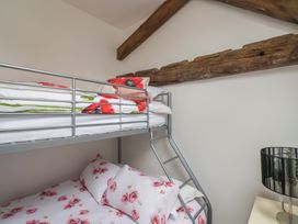 A bedroom with a metal bunk bed with floral bedding and wooden beams on the ceiling at Poppy Cottage in Aylesbeare