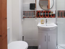 A bathroom with a toilet sink vanity round mirror towel radiator and shower cubicle at Poppy Cottage in Aylesbeare