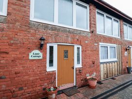 Exterior view of a brick cottage with a brown door two potted plants and multiple windows at Lime Cottage in Aylesbeare