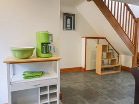 A kitchen area with a green coffee maker and bowl on a cart under wooden stairs at Lime Cottage in Aylesbeare