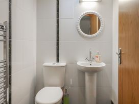 A bathroom with a toilet, pedestal sink, round mirror, and towel radiator at Lime Cottage in Aylesbeare