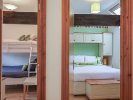 Two bedrooms with bunk beds on the left and a double bed with cupboards above on the right at Lime Cottage in Aylesbeare