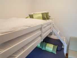 A bunk bed with white frame and green pillows in a bedroom at Lime Cottage in Aylesbeare