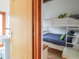 A small bedroom with bunk beds and pillows next to a bathroom with a sink at Lime Cottage in Aylesbeare