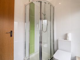 A bathroom with a corner shower enclosure and a toilet with toilet paper rolls on top at Lime Cottage in Aylesbeare