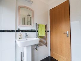 A bathroom with a pedestal sink a mirror towel rack with a green towel and a wooden door at Lime Cottage in Aylesbeare