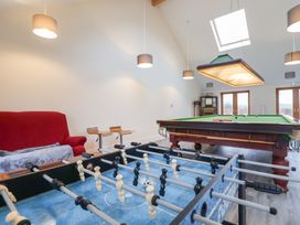 A game room with a foosball table a pool table a red sofa and two wooden stools at Lime Cottage in Aylesbeare