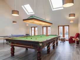 A game room with a snooker table a ping pong table and a red armchair at Lime Cottage in Aylesbeare