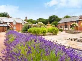 A courtyard with lavender plants a water fountain and brick buildings at Lime Cottage in Aylesbeare