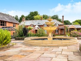 A courtyard with a three-tier stone fountain surrounded by stone paving and plants in front of brick houses at Lime Cottage in Aylesbeare