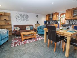 An open living and kitchen area with a dining table set for four wooden coffee table sofas and kitchen cabinets at Oak Cottage in Aylesbeare