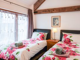 A bedroom with two single beds with floral bedding and a nightstand with a lamp and clock at Oak Cottage in Aylesbeare