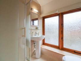 A bathroom with a pedestal sink mirror shower enclosure and frosted windows at Oak Cottage in Aylesbeare