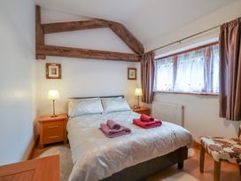 A bedroom with a double bed lamps and a window with curtains at Oak Cottage in Aylesbeare