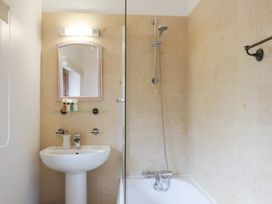 A bathroom with a sink and mirror and a bathtub with a shower at Oak Cottage in Aylesbeare