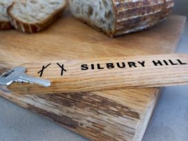 A wooden keychain with a silver key and bread on a wooden chopping board at The Stables in Galteemore Farm in Avebury near Marlborough