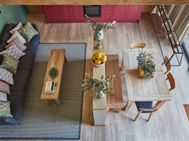 A living area with a blue sofa and patterned cushions a wooden coffee table a wooden dining table with chairs and a basket of flowers at The Stables Galteemore Farm in Avebury near Marlborough