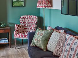 A living room with patterned armchair sofa with cushions and a side table at The Stables in Galteemore Farm in Avebury near Marlborough