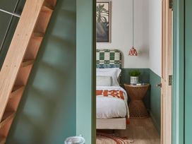 A bedroom with a bed and a bedside table with a plant and a hanging lamp at The Stables in Galteemore Farm in Avebury near Marlborough