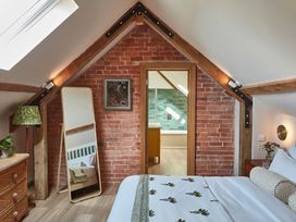 A bedroom with a bed a standing mirror a wicker chest of drawers and a lamp at The Stables in Galteemore Farm in Avebury near Marlborough