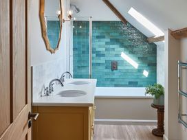 A bathroom with a double sink vanity a bathtub with teal tiles and a skylight at The Stables in Galteemore Farm in Avebury near Marlborough